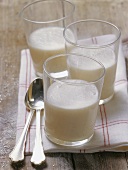 Buttermilk in three glasses on a tea towel with spoons
