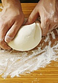 Kneading pasta dough on floured wooden board
