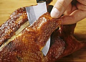 Cutting the crispy skin from a whole Peking duck