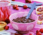 Cranberry jam in a bowl with spoon and on bread
