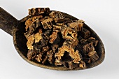 Pieces of dried gentian root on a wooden spoon