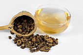 Getrocknete Enzianwurzel-Stücke mit Teesieb und Tee