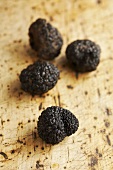 Four Périgord truffles on wooden background