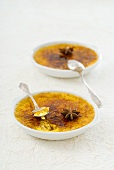 Two dishes of crème brûlée with star anise