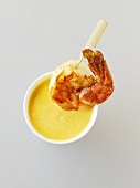 Fried prawn on a wooden skewer with coconut curry sauce