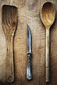 Two wooden spoons and a knife on a wooden chopping board