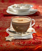 Hot chocolate in a glass cup and saucer, cinnamon stars