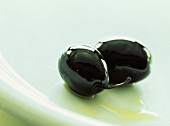 Zwei schwarze in Öl eingelegte Oliven