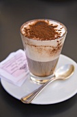 Ein Glas Cappuccino mit Kakao bestäubt