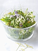 Herb salad with edible flowers in a glass bowl