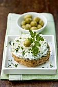 Herb quark with sprouts on a wholemeal bread roll, olives