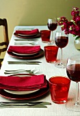 Gedeckter Tisch mit Weingläsern und Blumenstrauss in rot