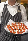 Waiter carrying a tray of salmon canapés