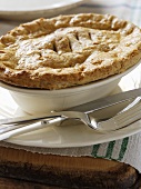 Beef pie in a pie dish with knife and fork