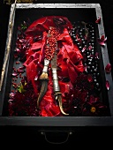 Red peppercorns in a drawer with flowers, fabric, cutlery