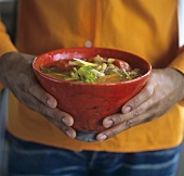 Mann hält eine Schale mit indischer Gemüsesuppe