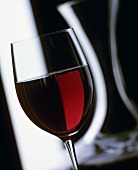 A glass of red wine with carafe
