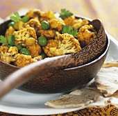Cauliflower curry with peas in a wooden bowl
