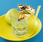 Avocado and olives on toast on a glass of water