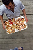 Man carrying a tray of barbecued seafood