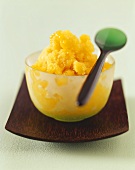Mango sorbet in a glass bowl with spoon