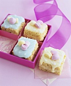 Small cakes with coloured icing in and beside gift box