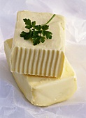 Two blocks of butter with parsley on paper