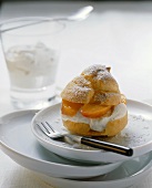 Profiterole filled with peaches and whipped cream