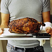 Whole duck on a board with carving knife and fork