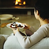 A woman on a sofa with a plate of blinis topped with beetroot and caviar