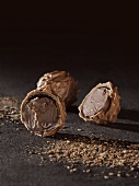 Whole and halved chocolate truffles on black background