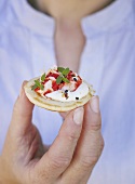 A woman holding a blini with crayfish