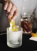 A bartender placing ice cubes in a glass