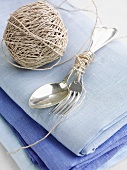 Cutlery tied with kitchen twine on a blue linen cloth