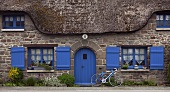 Steinhaus mit Reetdach und blaue Fensterrahmen