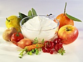 Quark in glass bowl, surrounded by fruit and vegetables