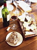 Red wine, bread and cheese board on table