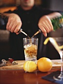 Barmixer giesst Alkohol in Cocktailglas