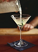 Gimlet with cucumber slices being poured into a glass
