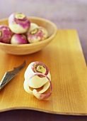 Peeled turnip, bowl of unpeeled turnips behind