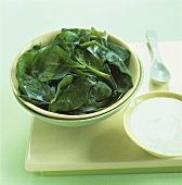 Cooked spinach leaves and cinnamon yoghurt in bowls