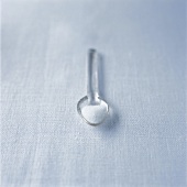 Sugar in transparent plastic spoon on white background