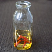Chilli oil with whole chillies in glass bottle