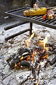 Sausages and corn on the cob on a barbecue