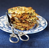 A pile of potato pancakes on plate with serving tongs