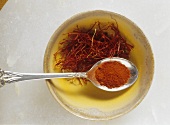 Saffron threads in dish, saffron powder on spoon