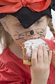 Girl in fancy dress biting into a doughnut (Carnival)