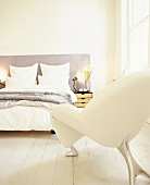 Ein weißer Designsessel im hellen Schlafzimmer