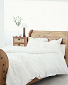 Ein rustikales Doppelbett mit weißem Bettbezug im hellen Schlafzimmer