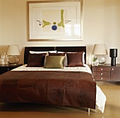 Ein Doppelbett mit Brauner Wildlederdecke am Bettende und passende Nachttischkonsolen mit Leselampen